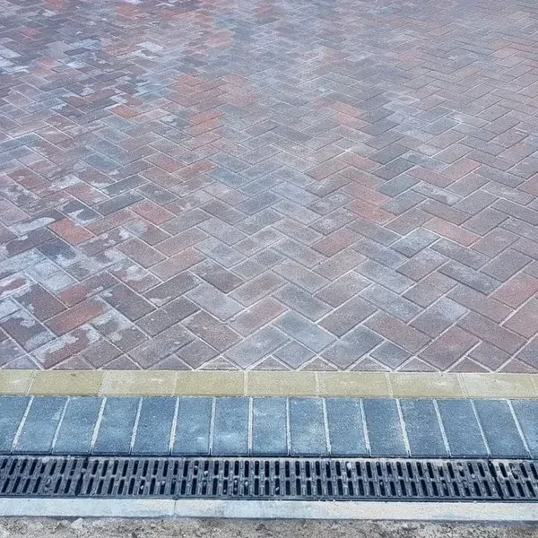 Grey herringbone block paving with a channel drain