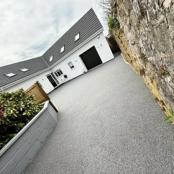 Grey resin bound driveway beside a white house