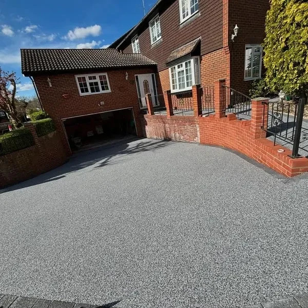 Grey resin bound driveway in front of a brick house