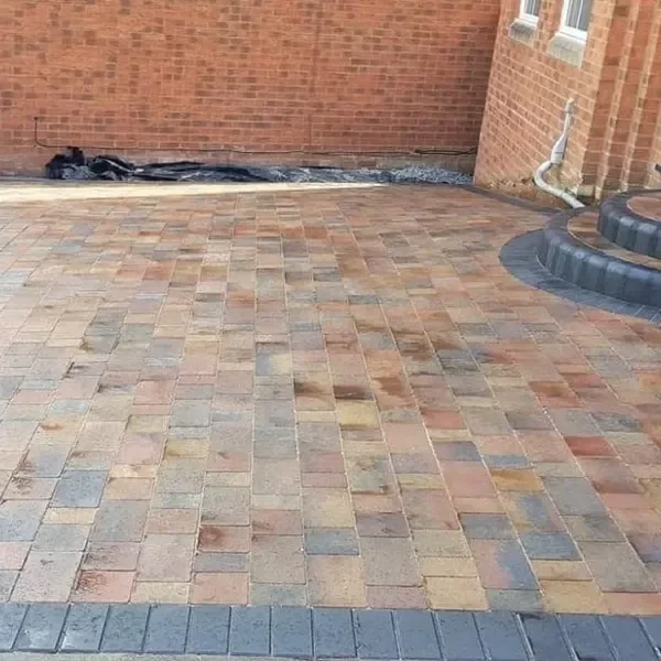 Multi-coloured block paving driveway against a brick wall