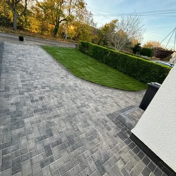 Curved grey block paving driveway and lawn
