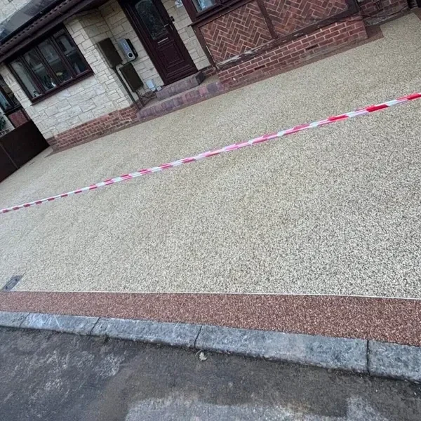 Pale resin bound driveway with a brick edge