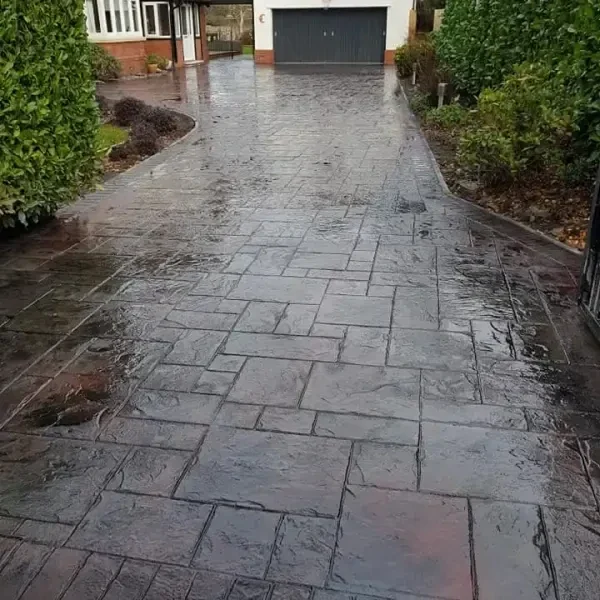 Grey imprinted concrete drive between hedges