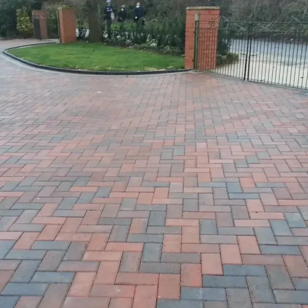 Red and charcoal herringbone driveway with a curved border