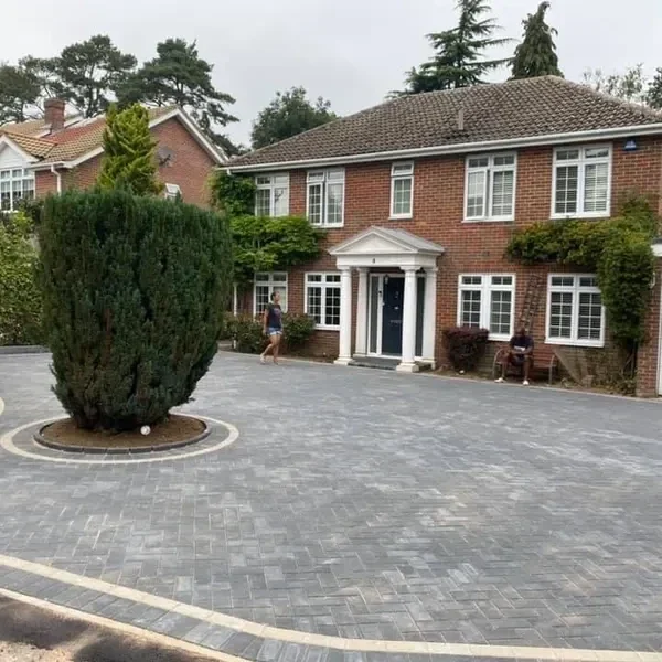 Grey block paving driveway with a circular planted bed