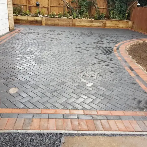 Charcoal herringbone block paving with a red edge