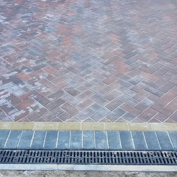 Grey herringbone block paving with a channel drain