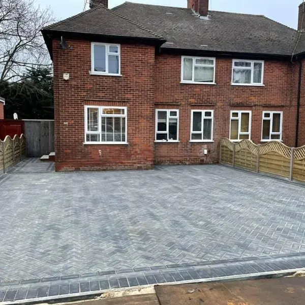 Grey block paving driveway in front of a brick house