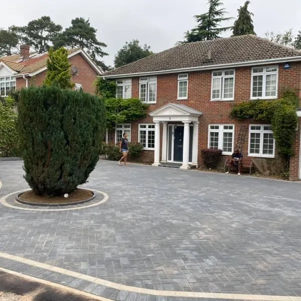 Grey block paving driveway with a circular planted bed