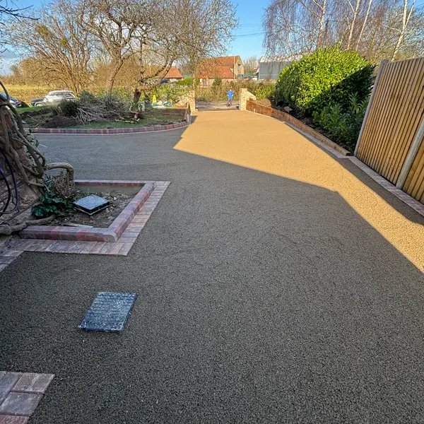 Resin bound and dark tarmac driveway with a brick border