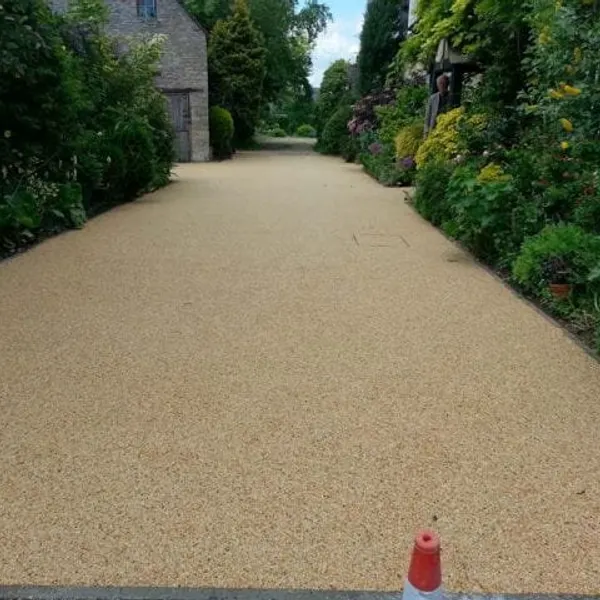 Long buff resin bound driveway between planted borders