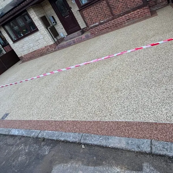 Pale resin bound driveway with a brick edge
