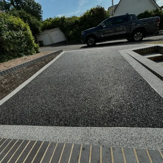 Black tarmac driveway with block edging and a channel drain